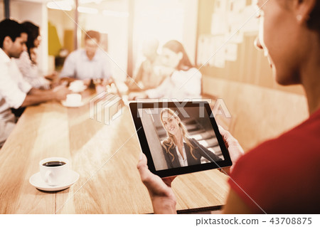 Composite image of woman holding digital tablet with colleagues in background Composite image of woman holding digital tablet with colleagues in background 43708875