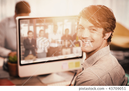 Composite image of happy businessman sitting at computer desk 43709051