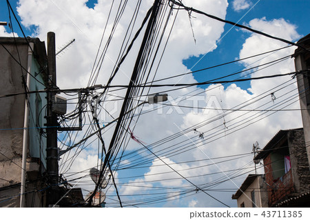 Electric wires in a slum with cloudy sky. Electric wires in a slum with cloudy sky. 43711385