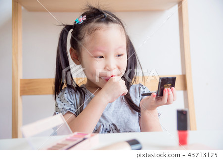 girl applying red color lipstick on her lips girl applying red color lipstick on her lips 43713125