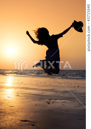 Girl jumping on the beach at sunset Girl jumping on the beach at sunset 43715840