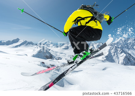 A skier in full sports equipment jumps into the abyss from the top of the glacier against the A skier in full sports equipment jumps into the abyss from the top of the glacier against the 43716566