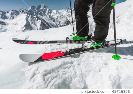Foot athlete skier in professional ski boots on snow. A close-up of the skis on the athlete's legs Foot athlete skier in professional ski boots on snow. A close-up of the skis on the athlete's legs 43716568