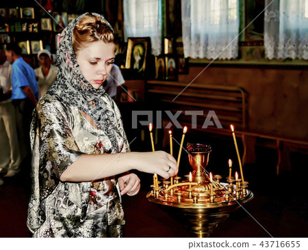 Young woman in church puts a candle and pray Young woman in church puts a candle and pray 43716655