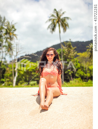 Young woman in red bikini sitting on the fine sand 43722281