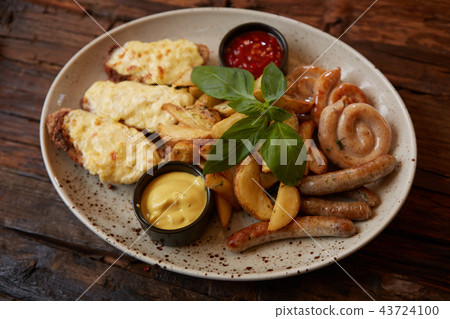 Grilled assorted sausages with French fries, bruschettes with cheese and sauces. Grilled assorted sausages with French fries, bruschettes with cheese and sauces. 43724100
