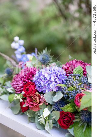 Elongated floral arrangement in vintage metal vase. table setting. Blue and red color. Gorgeous 43725696