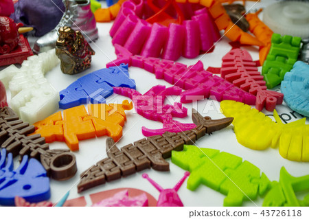 Many bright multi-colored objects printed on 3d printer lie on flat surface Many bright multi-colored objects printed on 3d printer lie on flat surface 43726118