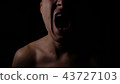 Angry man. A screaming evil expression. Close-up of the man's face in the dark. 43727103