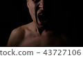 Angry man. A screaming evil expression. Close-up of the man's face in the dark. 43727106