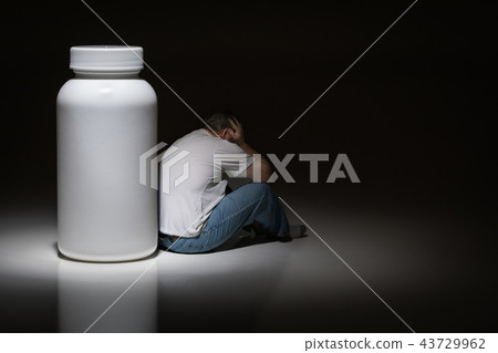 Man Holding Head Next To Blank Medication Bottle 43729962