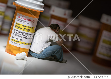 Man Holds Head Sitting by Hydrocodeon Pill Bottle 43729963