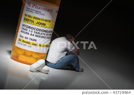 Man Holds Head Sitting by Hydrocodeon Pill Bottle 43729964