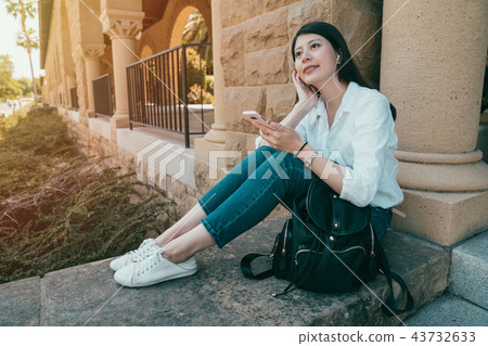 female sitting on stone and listen to music 43732633
