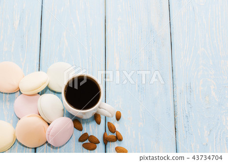 A Cup of coffee with Marshmallows on a light blue background next to almond nuts. Place for text. 43734704