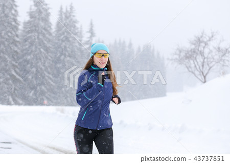 Young woman running on the mountain road in winter 43737851