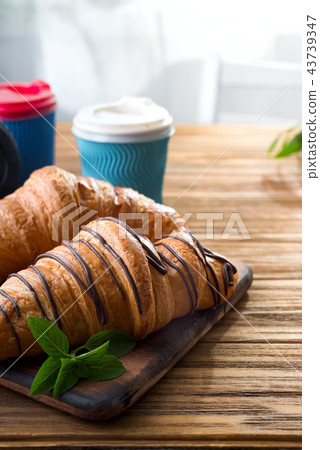 cups of coffee and two croissants on the street in Croissant Cafe. Inscripton on cup - Croissant 43739347