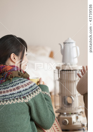 Rear view of a woman warmed by a stove 43739586