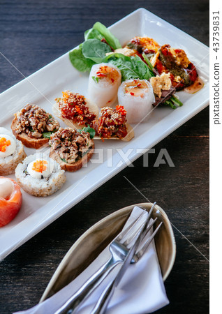 Asian canapes appetizer on white plate, wood table Asian canapes appetizer on white plate, wood table 43739831