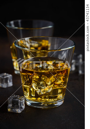 Glass of whiskey with ice on dark background  43741134