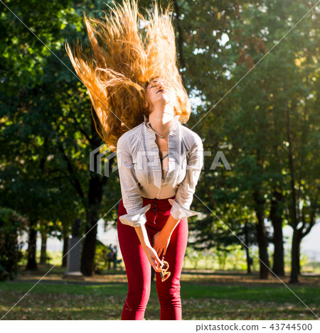 Woman swinging hair in the park, healthy hair concept Woman swinging hair in the park, healthy hair concept 43744500