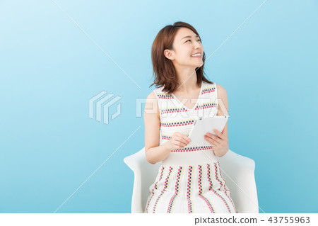 A woman watching a tablet in a room A woman watching a tablet in a room 43755963
