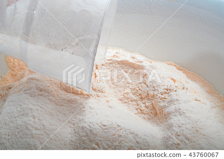 Flour in white Cup with a measuring Cup. 43760067