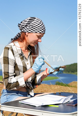 Beautiful girl archaeologist carefully clears the find with a brush 43761529