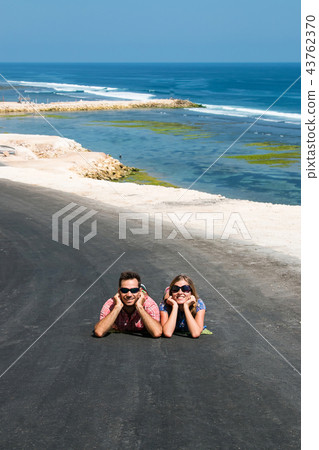 traveller couple lay down on black road, ocean  43762370