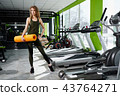 Girl standing in the gym holds a mat 43764271