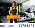 Girl standing in the gym holds a mat 43764273