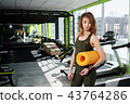 Girl standing in the gym holds a mat 43764286