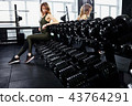 A young girl is sitting on a dumbbell 43764291