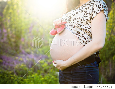 Close up of pregnant woman with baby little shoes 43765393