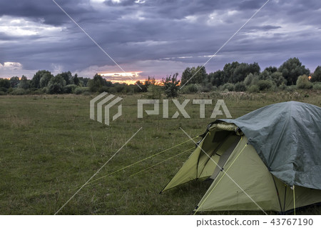 Tourist tent in the meadow in the evening. Tourist tent in the meadow in the evening. 43767190