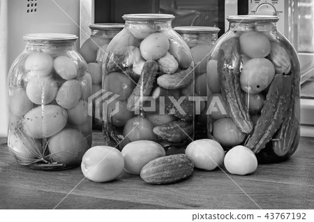 Canned tomatoes and cucumbers in large glass jars. Black-and-white image. Canned tomatoes and cucumbers in large glass jars. Black-and-white image. 43767192