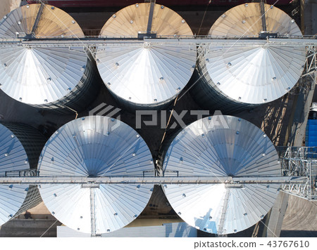 Agricultural Silo. Storage and drying of grains, wheat, corn, soy, against the blue sky with clouds. Agricultural Silo. Storage and drying of grains, wheat, corn, soy, against the blue sky with clouds. 43767610
