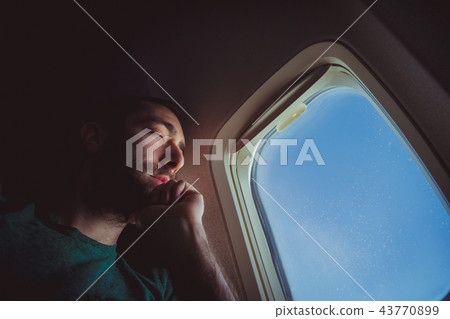 Young man resting and sleeping on an airplane 43770899