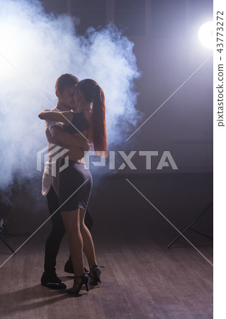Skillful dancers performing in the dark room under the concert light and smoke. Sensual couple 43773272