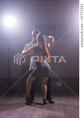 Skillful dancers performing in the dark room under the concert light and smoke. Sensual couple Skillful dancers performing in the dark room under the concert light and smoke. Sensual couple 43773383