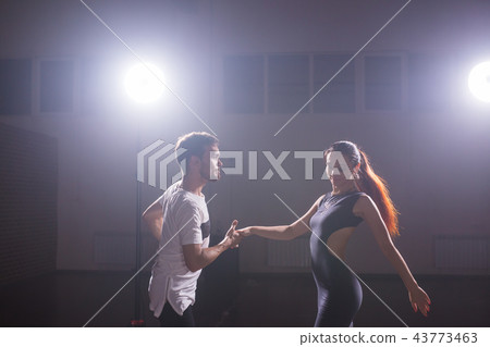 Skillful dancers performing in the dark room under the concert light and smoke. Sensual couple 43773463