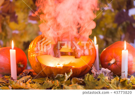Halloween pumpkin lantern with dry leaves, candles and smoke 43773820
