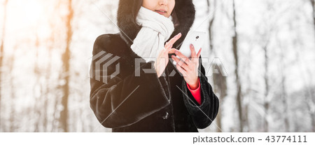 Technology, people and winter concept - Close up of female hands with smartphone and winter 43774111