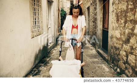 Mother and baby traveling in Mediterranean old town with a stroller on vacation Mother and baby traveling in Mediterranean old town with a stroller on vacation 43774650