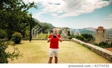 Photographer in red tshirt takes photo in Mediterranean scenery on vacation 43774785