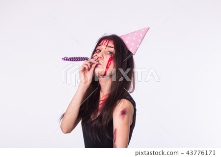 Halloween and carnival concept - young woman with blood on face celebrate holidays with whistle 43776171