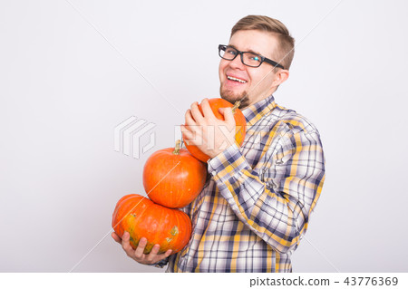 Smiling man holding pumpkins over white background with copy space - harvest and autumn concept Smiling man holding pumpkins over white background with copy space - harvest and autumn concept 43776369