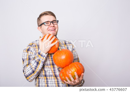 portrait of a young farmer holding a pumpkins on a light background studio portrait of a young farmer holding a pumpkins on a light background studio 43776607