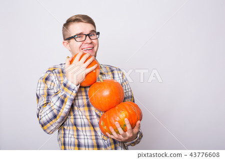 portrait of a young farmer holding a pumpkins on a light background studio portrait of a young farmer holding a pumpkins on a light background studio 43776608