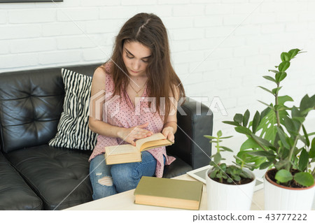 Education and people concept - young student woman sitting on the dark couch with book 43777222